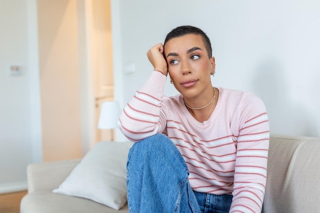 Mujer joven relajándose en su sofá en casa en la sala de estar Hermosa mujer sola en la sala de estar Señora africana sonriente sentada en el sofá