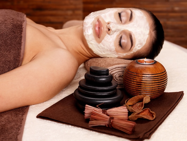 Foto gratuita mujer joven relajante con máscara cosmética en la cara en el salón de belleza en el interior