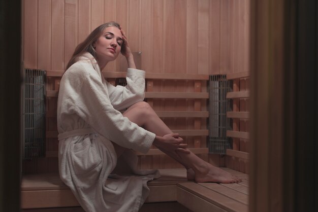 Mujer joven relajante en una sauna de madera