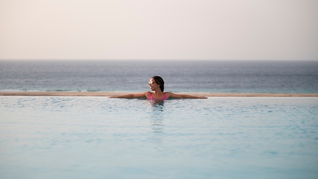 Mujer joven, relajante, solo, en la piscina