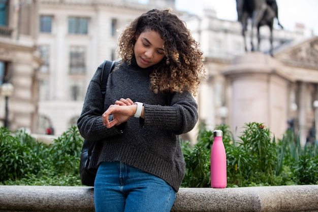 Mujer joven revisando su reloj en la ciudad