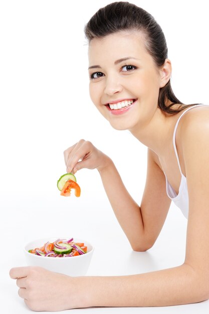 Mujer joven riendo comiendo ensalada saludable - aislado en blanco