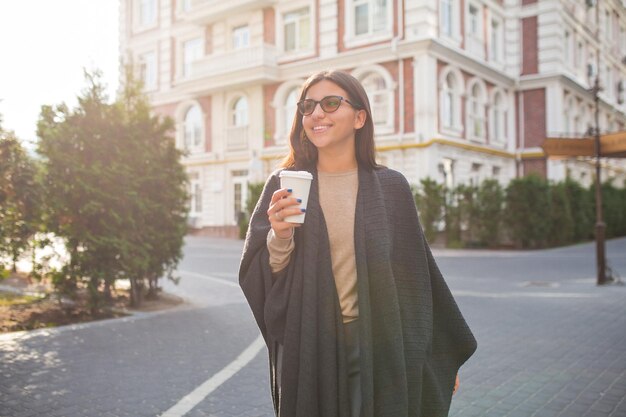 Mujer joven riendo con gafas caminando al aire libre y escuchando música Hipster girl pasa tiempo afuera en la ciudad