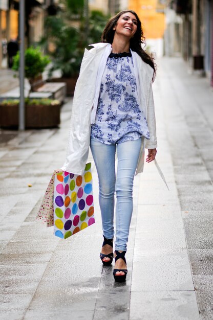 Mujer joven riendo mientras sujeta sus bolsas de la compra