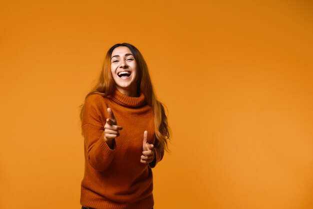 Mujer joven riendo señala con los dedos en la parte delantera