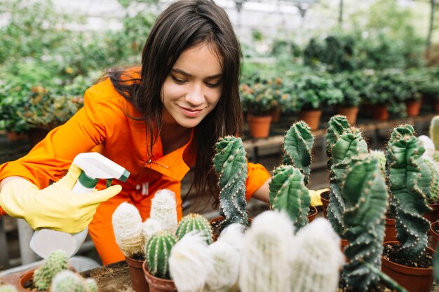 Mujer joven rociando agua en las plantas de cactus