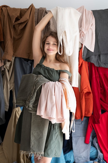 Mujer joven rodeada de montones de ropa