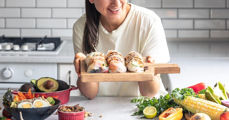 Foto gratuito una mujer joven con rollitos de primavera en papel de arroz en la cocina