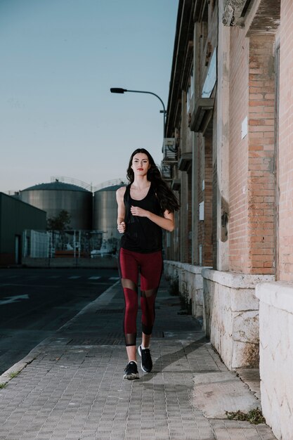 Mujer joven en ropa deportiva corriendo en la calle