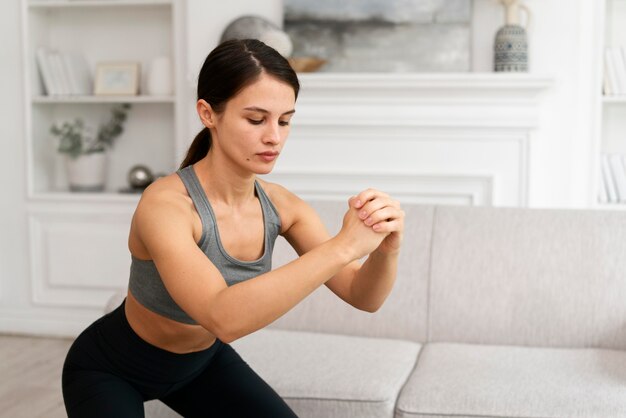 Mujer joven en ropa deportiva haciendo ejercicio en casa