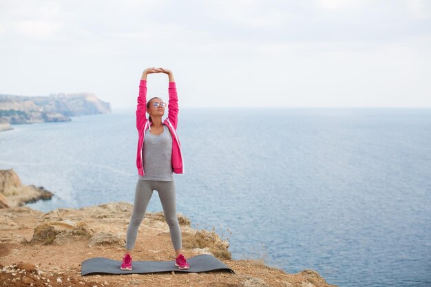 mujer joven en ropa deportiva haciendo yoga al aire libre