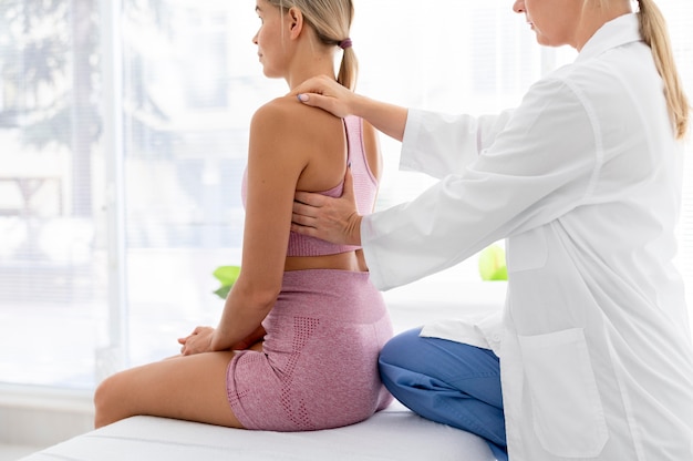 Mujer joven en ropa deportiva practicando un ejercicio en una sesión de fisioterapia