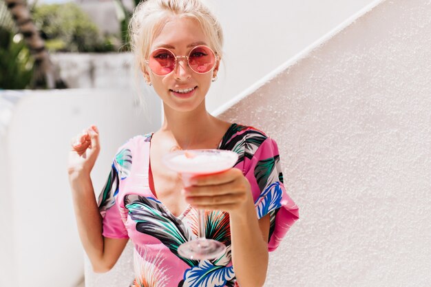 mujer joven en ropa elegante bebiendo cócteles en día de verano.