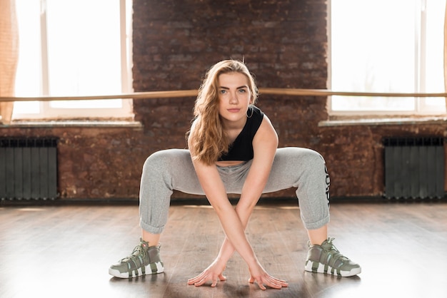 Foto gratuita mujer joven en ropa de fitness haciendo ejercicio antes de bailar en el estudio de danza