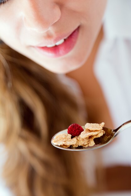 Mujer joven en ropa interior comiendo cereales. Aislado en blanco