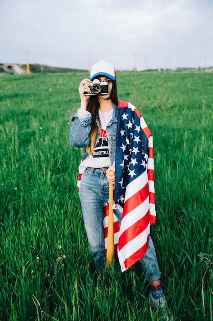 Mujer joven en ropa de jeans y gorra de colores con dispositivo vintage