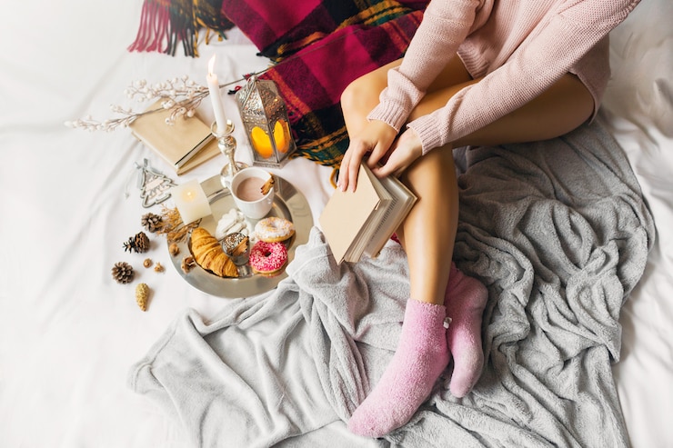 Foto gratuito mujer joven en ropa de lana abrigada está sentada en su cama en la luminosa casa soleada