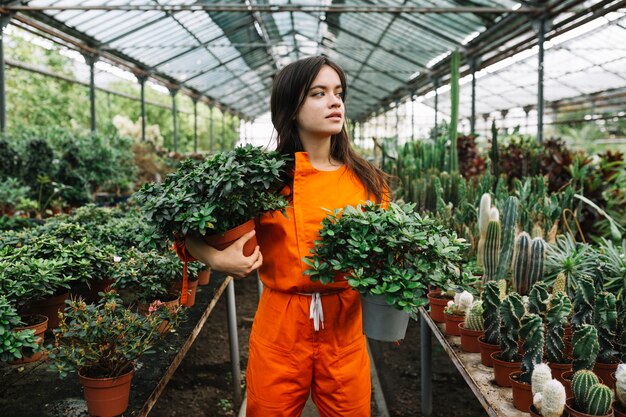 Mujer joven en ropa de trabajo con plantas en maceta