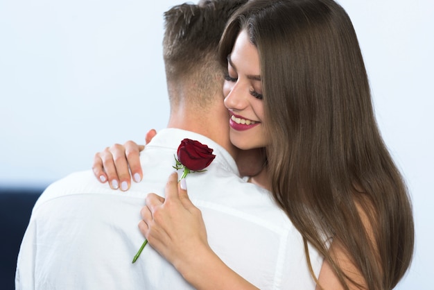 Mujer joven con rosa abrazando a hombre