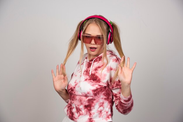 Mujer joven rubia en auriculares rosa jugando con su cabello.