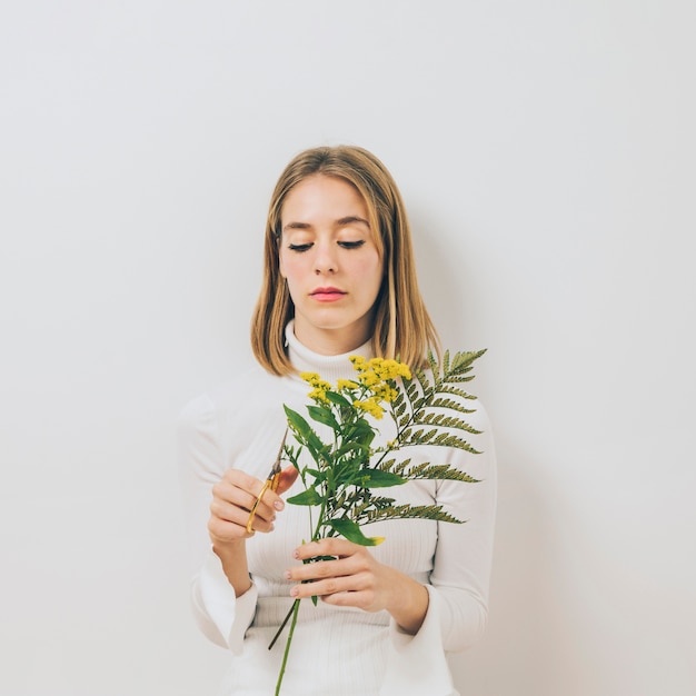 Foto gratuita mujer joven rubia cortando flores con tijeras