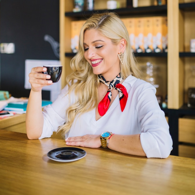 Mujer joven rubia disfrutando de la taza de café en la cafetería