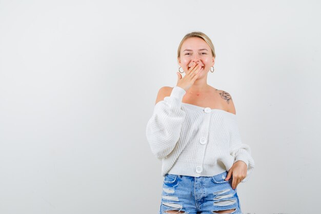 Mujer joven rubia en una rebeca blanca