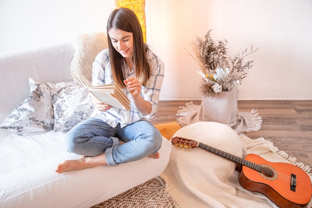 Mujer joven en la sala de estar con una guitarra.