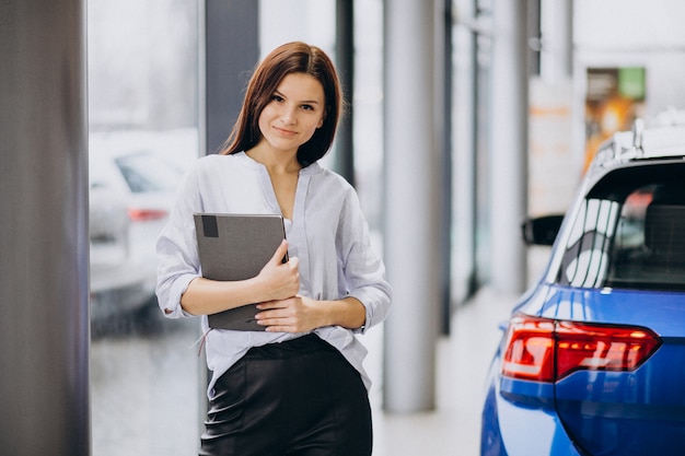 Mujer joven en una sala de exposición de automóviles elegir un automóvil