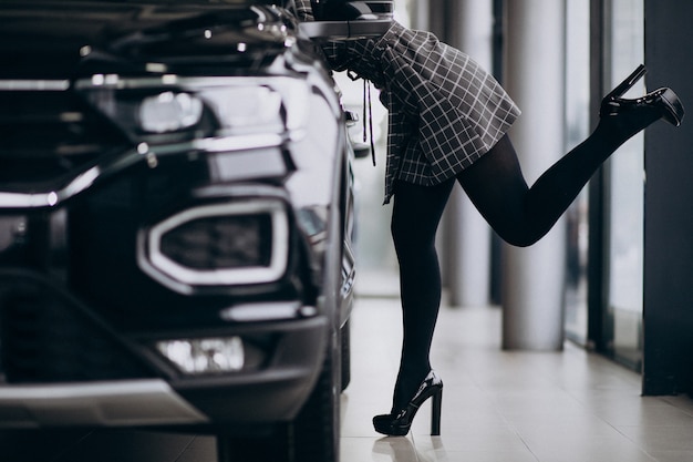 Mujer joven en una sala de exposición de automóviles elegir un automóvil