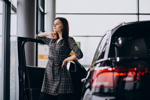 Mujer joven en una sala de exposición de automóviles elegir un automóvil