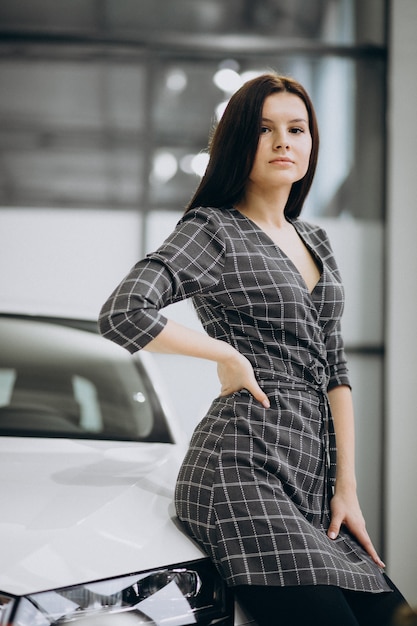 Mujer joven en una sala de exposición de automóviles elegir un automóvil