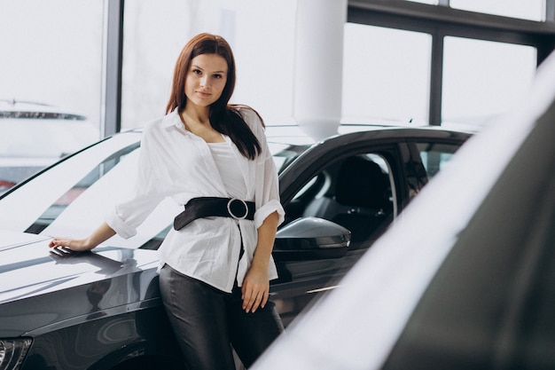 Mujer joven en una sala de exposición de automóviles elegir un automóvil