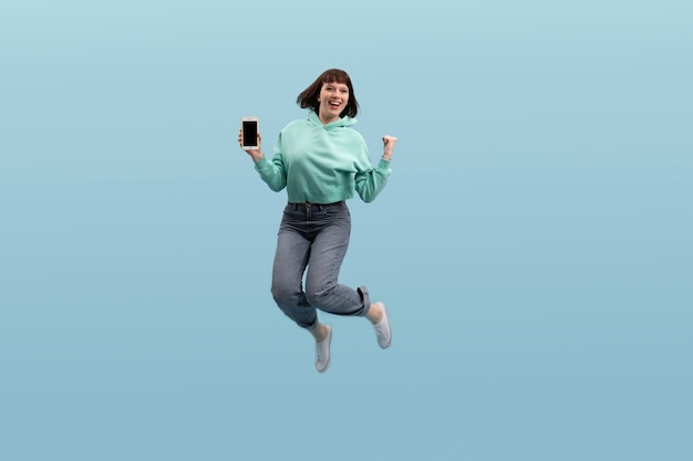 Mujer joven saltando aislado en azul