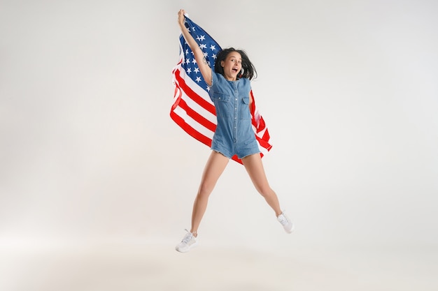 Mujer joven saltando con la bandera de los Estados Unidos de América aislado en blanco studio.
