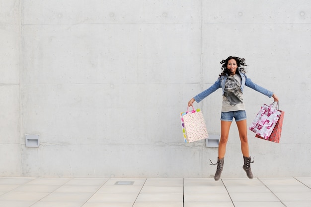 Mujer joven saltando con las bolsas de la compra