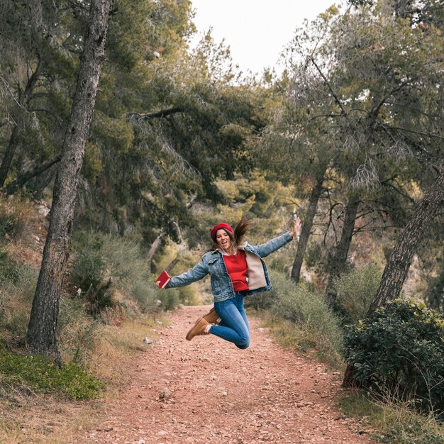 Mujer joven saltando por encima del sendero en la montaña