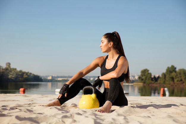 Mujer joven sana descansando después de practicar en la playa.