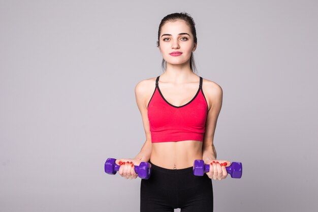 Mujer joven sana con pesas ejercicio aislado en la pared blanca. concepto de gimnasio de fitness