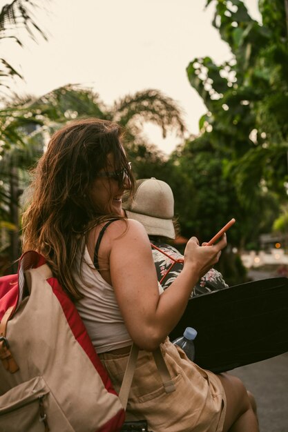 Una mujer joven en un scooter viaja toma fotos por teléfono.