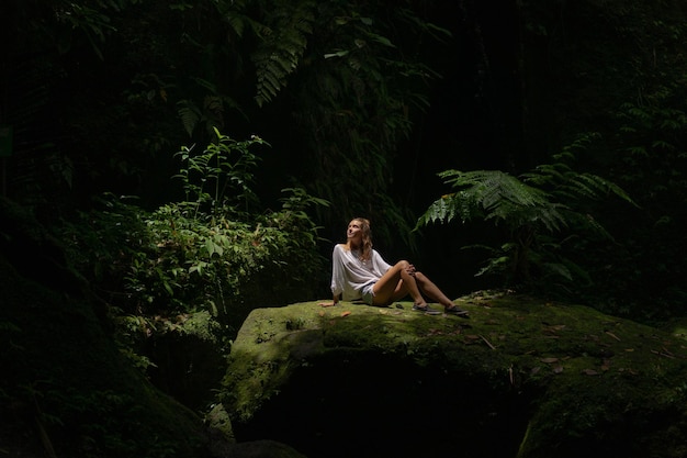 Foto gratuita una mujer joven en la selva deja escapar bocanadas de humo vape