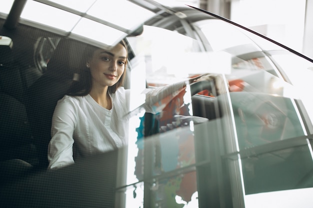 Foto gratuita mujer joven sentada en un automóvil en una sala de exposición de automóviles