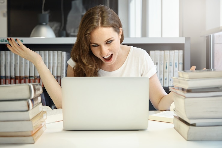 Foto gratuito mujer joven sentada en la biblioteca con un portátil