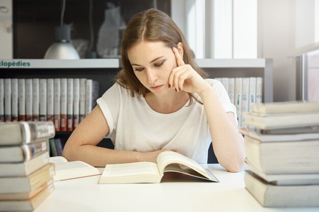 Mujer joven sentada en la biblioteca con un portátil