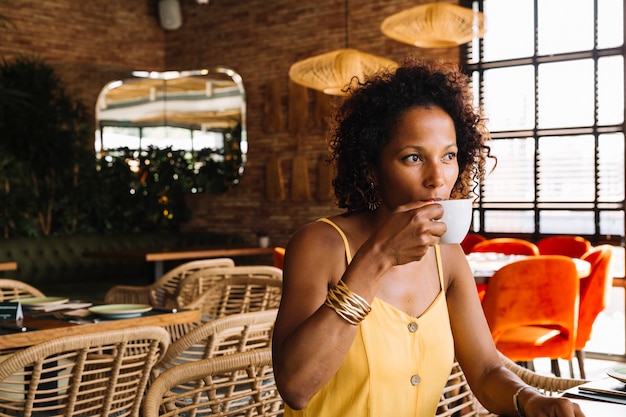 Foto gratuita mujer joven sentada en el café tomando café