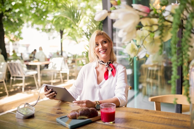 Mujer joven sentada en un café usando tableta digital