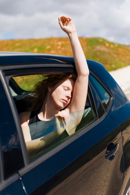 Mujer joven sentada en un carro con los ojos cerrados.