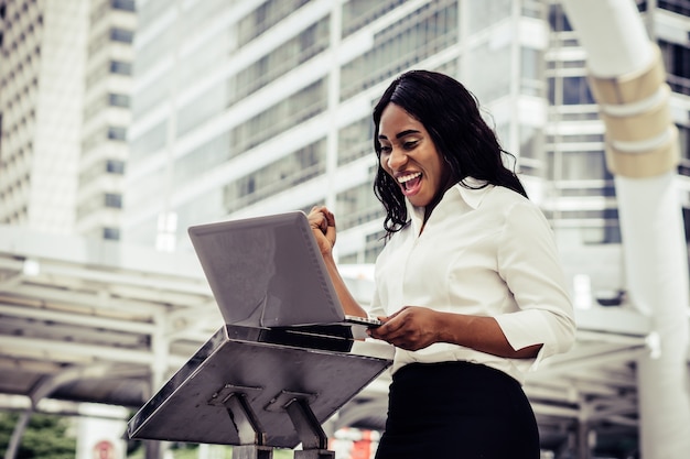 Mujer joven sentada en la escalera con la computadora portátil. Mujer trabajando en equipo portátil en un exterior