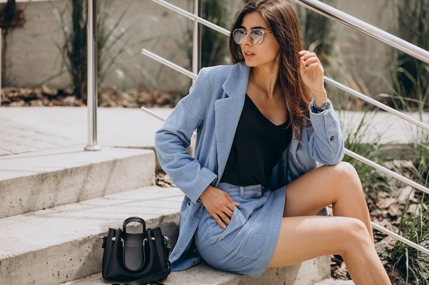 Mujer joven sentada en las escaleras con un traje azul