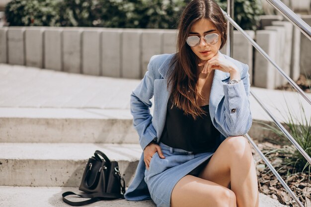 Mujer joven sentada en las escaleras con un traje azul